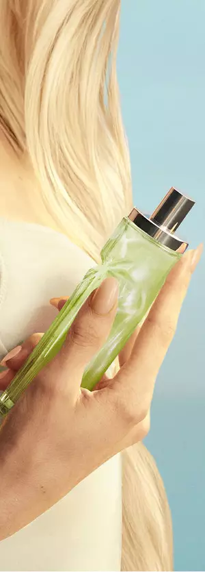 Visuel du nouveau Starlicious Pistachio Praline, avec un mannequin aux longs cheveux blonds et aux yeux bleus, portant une robe jaune pâle et tenant le flacon de parfum Pistachio Praline.
