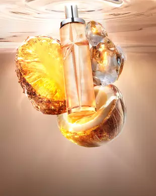 Nature morte du nouveau Starlicious Pineapple Musk mettant en scène le flacon en verre élancé entouré de ses ingrédients clés : une tranche d’ananas scintillante, une noix de coco ouverte et du musc cristallin, sur un fond d’eau ondulante chaude et lumineuse.